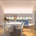 spacious double height kitchen with uplit cabinets and dining table in the foreground