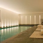 large indoor pool with uplights to side wall and lit slots at the end