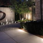 view to garden with uplit contemporary water feature, water jets and lit paving