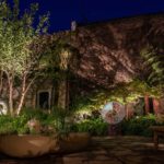 Dramatic shadows cast across brick wall by lighting planting and multi stem trees